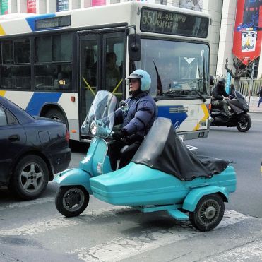 A lovely lady with a turquoise vespa with a sidecar